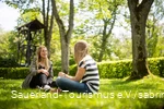Two friends are sitting on the grass and chatting.
