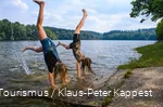 Zwei Mädchen machen Handstand am Ufer einer Talsperre.