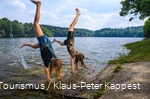 Zwei Mädchen machen Handstand am Ufer einer Talsperre.