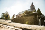 Zwei Rennradfahrer fahren um eine Kurve an einer Kirche vorbei.